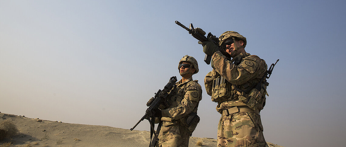 US soldier uses the optic on his rifle to observe Afghans in the distance Reuters