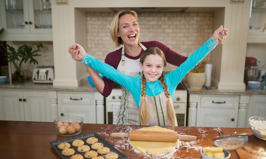 Portrait of happy mother and daughter having fun while preparing cookies in kitchen